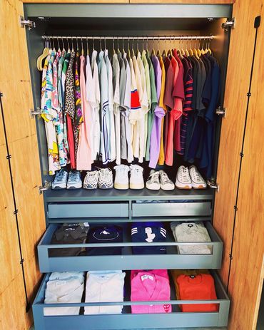A well-organized wardrobe containing shirts, sweaters, and shoes.