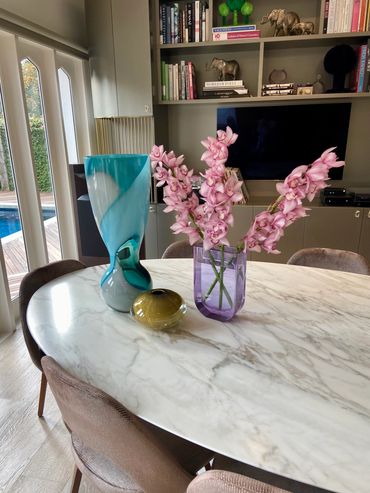 Modern dining table with vases and pink flowers.