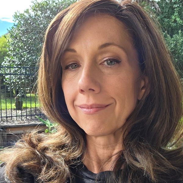 Woman with brown hair smiling slightly outdoors.