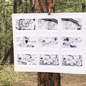 Black and white comic strips hanging on a tree outdoors.