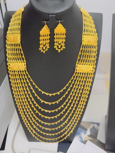 Intricate gold necklace and matching earrings displayed in 22k gold.