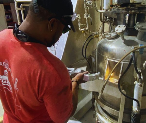 A worker using a laser to remove rust off of a tank