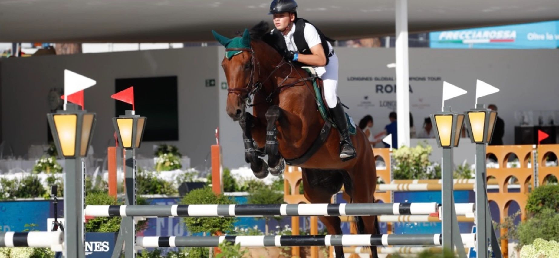 A rider and horse leap over an obstacle during a show jumping event.