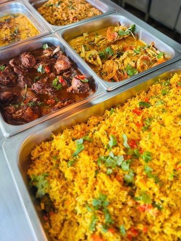 Buffet trays with seasoned rice, curried crab, and stewed meat dishes.