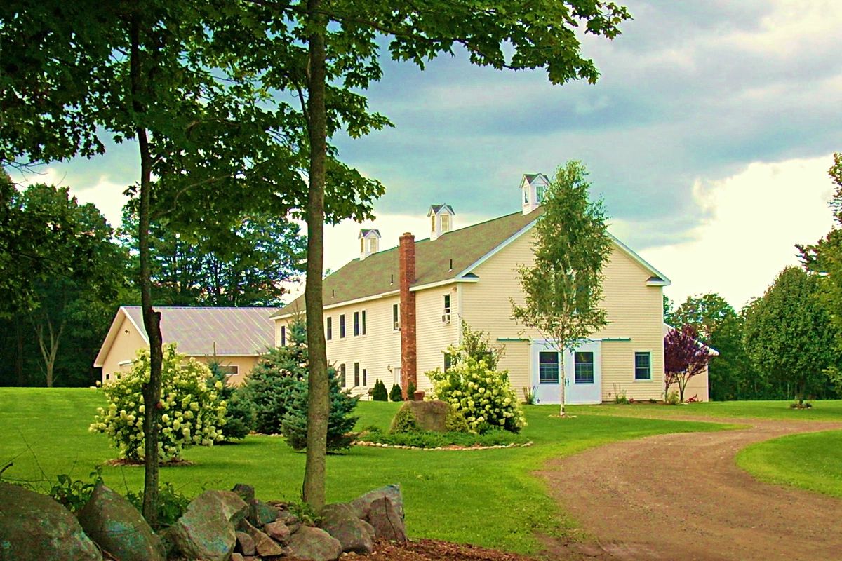 a driveway leading to a two story barn with attached indoor arena