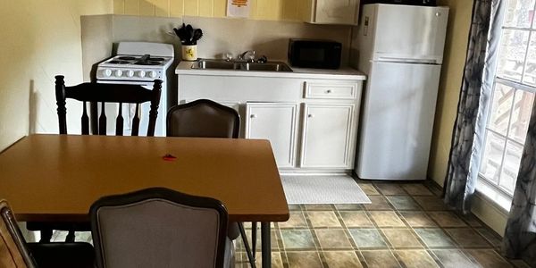 Small kitchen with dining table, chairs, stove, sink, microwave, and refrigerator.