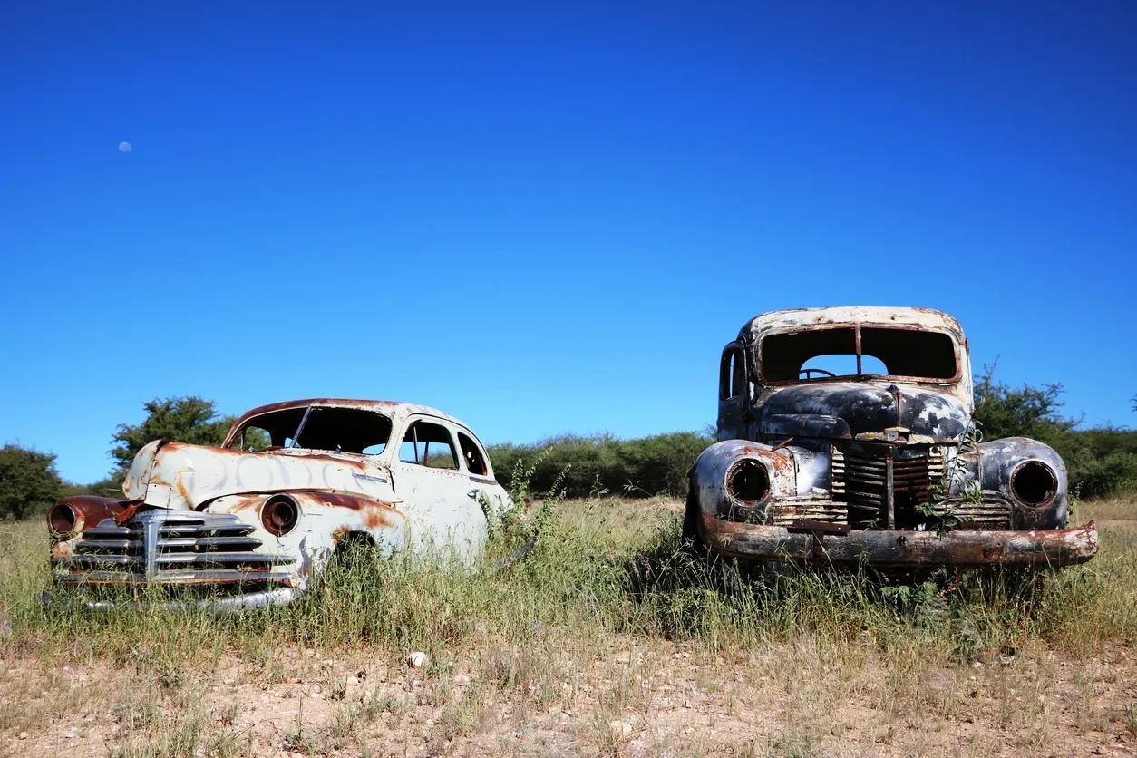 Junk cars sitting in a field.