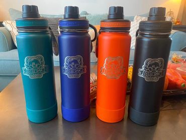 Four colorful ThermoFlask water bottles with Silly Yak Club logo on a table.
