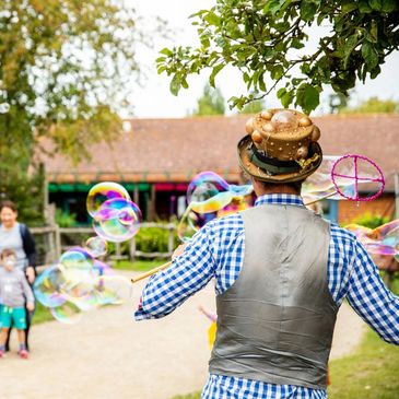 Man in a hat making bubbles for children outdoors.