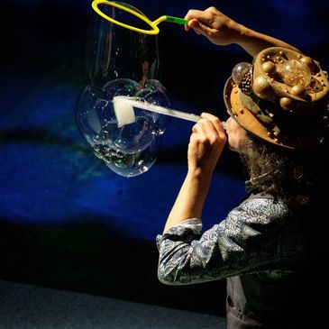 Person blowing bubbles with a yellow wand.