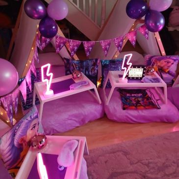 Cozy pink-themed indoor fort with balloons and neon lights.