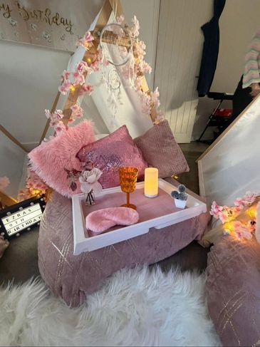 Cozy pink-themed indoor teepee setup with pillows and decor.