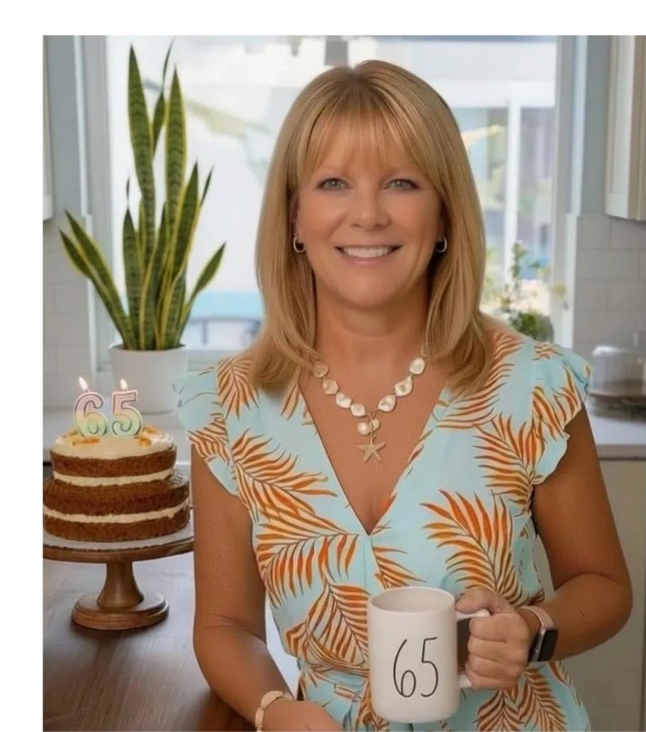 Woman celebrating her 65th birthday with cake and mug.