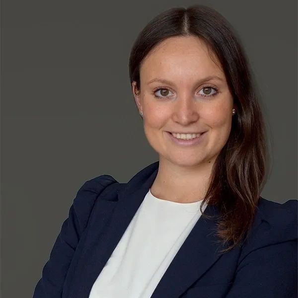 Rechtsanwältin Cosima Ebner. Lächelnd in marineblauem Blazer und weißer Bluse.