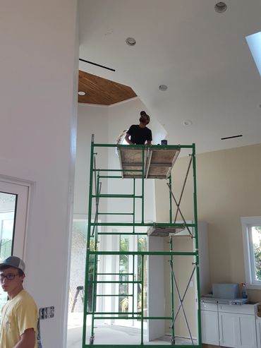 Man working on high scaffolding inside a house.