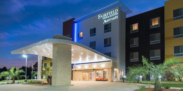 Fairfield Inn & Suites by Marriott hotel exterior at dusk with illuminated entrance.