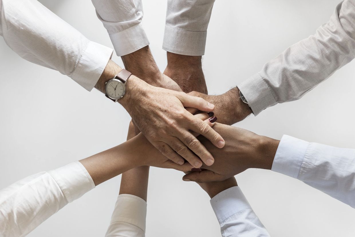 Diverse group stacking hands in unity and teamwork gesture.