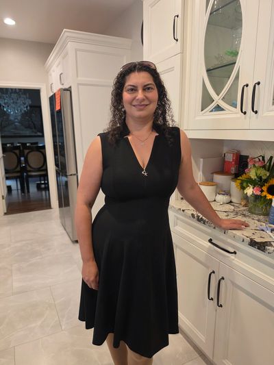 Woman in a black dress standing in a kitchen.
