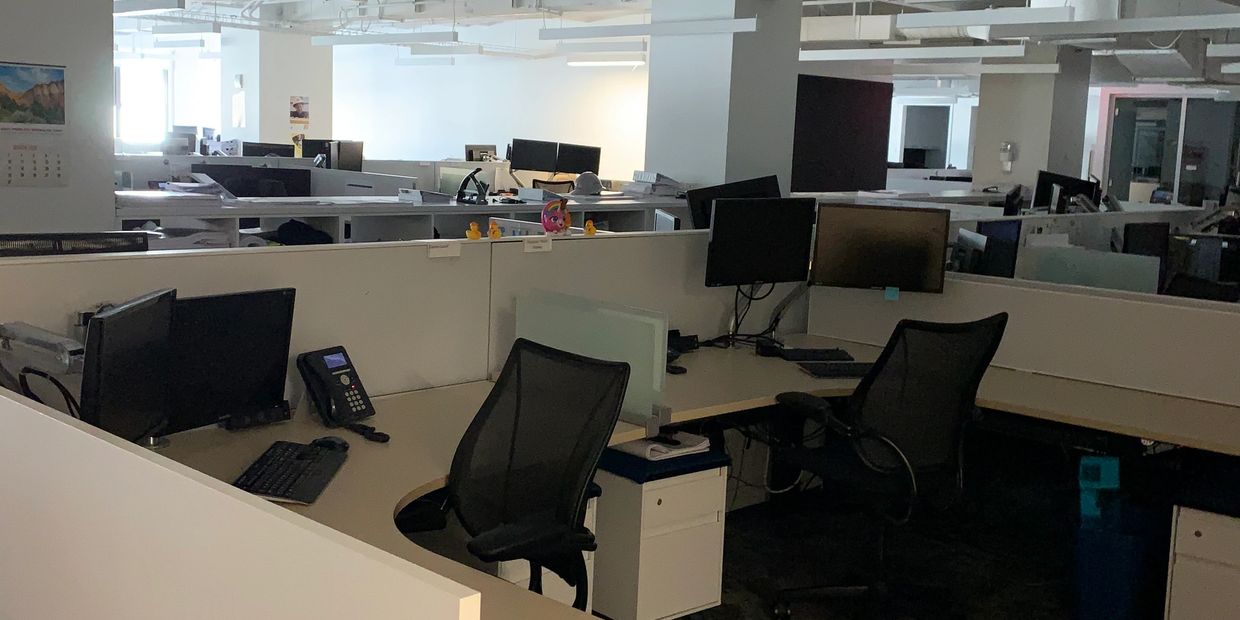 Empty modern office cubicles with computers and chairs.