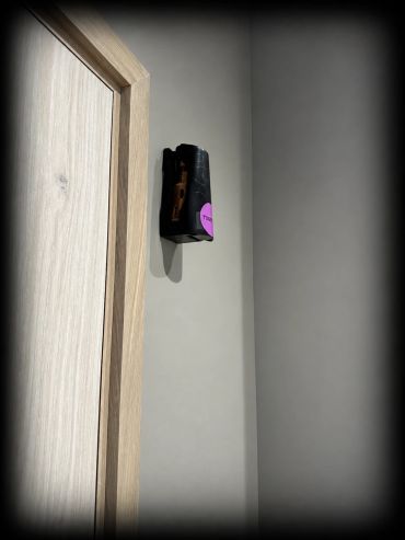 Side view of an Ethicork™ cork refill inside a black dispenser beside a TOGETHER.SPACE washroom door