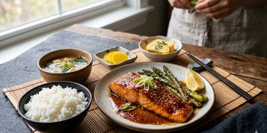 A delicious salmon dinner with rice, asparagus, and sides on a wooden table.