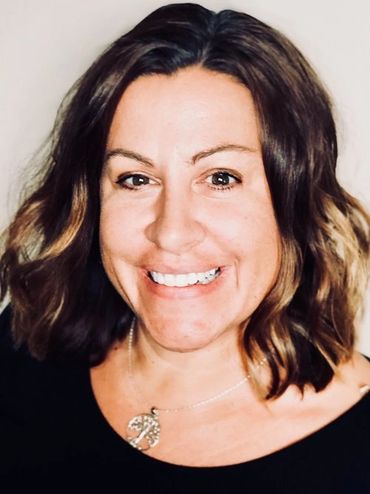Gina Merritt. A mid aged white woman with dark hair and black shirt smiles in a professional photo