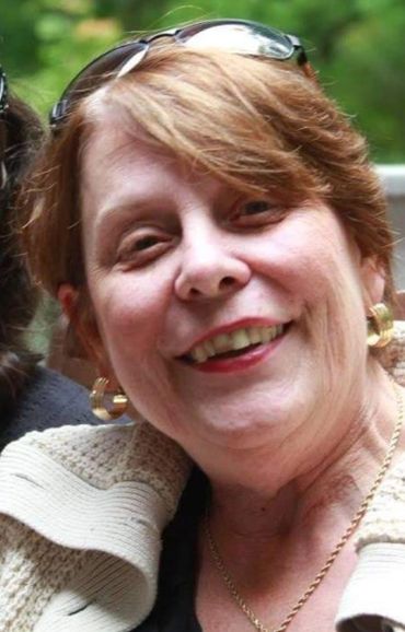 Kathy Armstrong. A senior white woman with reddish brown hair smiles from a deck.