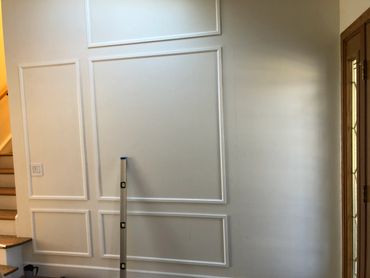 Interior wall with decorative molding and a level tool leaning against it.