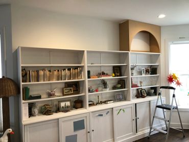 White bookshelf with various decor items and a step ladder nearby.