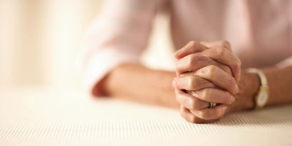Close-up of clasped hands on a table.