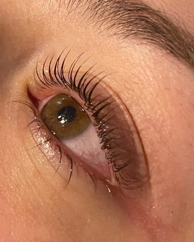 Close-up of a green eye with long eyelashes and detailed skin texture.