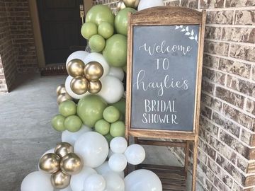Chalkboard sign with balloons welcoming guests to a bridal shower.