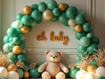 Teddy bear with green and gold balloon arch and 'oh baby' sign.