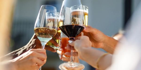 Friends clinking glasses in a cheerful toast outdoors.