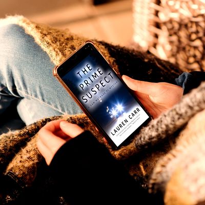 Person reading 'The Prime Suspect' by Lauren Carr on a smartphone.