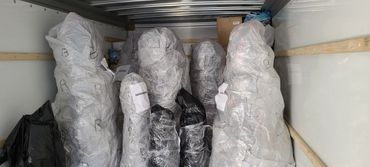 Several large objects wrapped in plastic inside a truck.