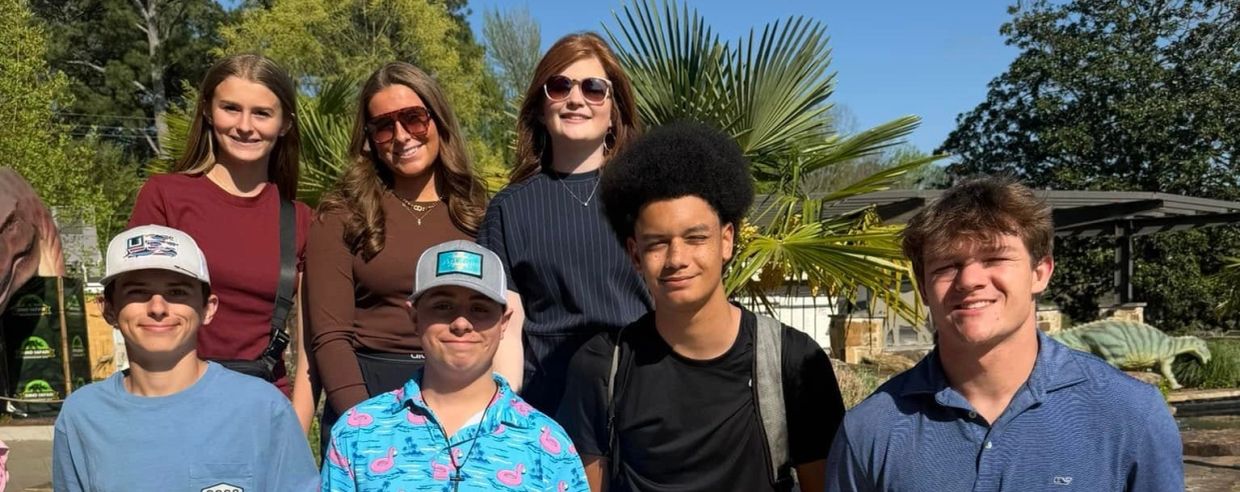 Group of seven diverse young people smiling outdoors.