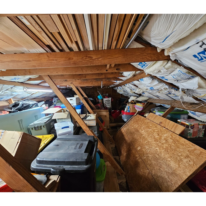 A cluttered attic filled with storage boxes and wooden beams.