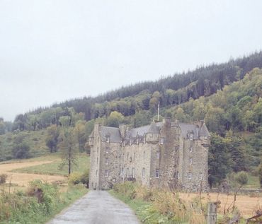 Historic stone castle nestled in a lush green hillside.