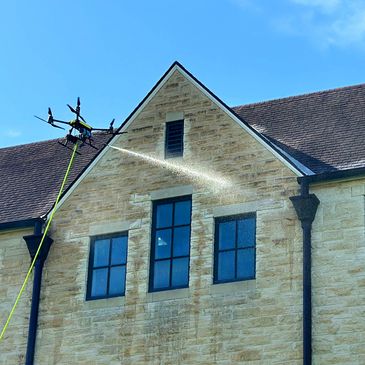 The facade and window of the private building are getting cleaned by a drone cleaning operator.