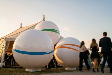 Evento al aire libre con esferas gigantes y carpa al atardecer