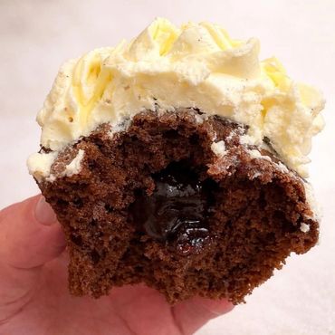 Chocolate cupcake with creamy yellow frosting and a gooey chocolate center.