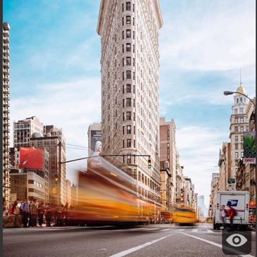 The iconic Flatiron Building in New York with blurred yellow taxis speeding by.