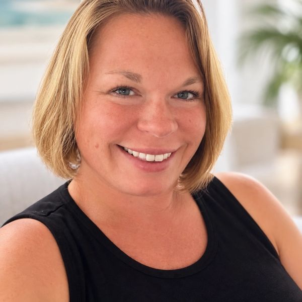 Smiling woman with short blonde hair and black top.