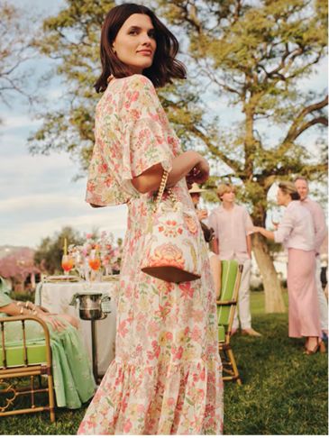 Woman in floral dress at outdoor garden party.