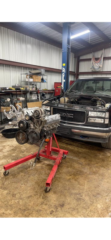 GMC truck in garage with engine on red stand.