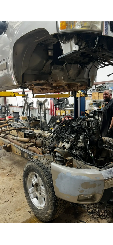 A truck undergoing major engine and chassis repair in a garage.