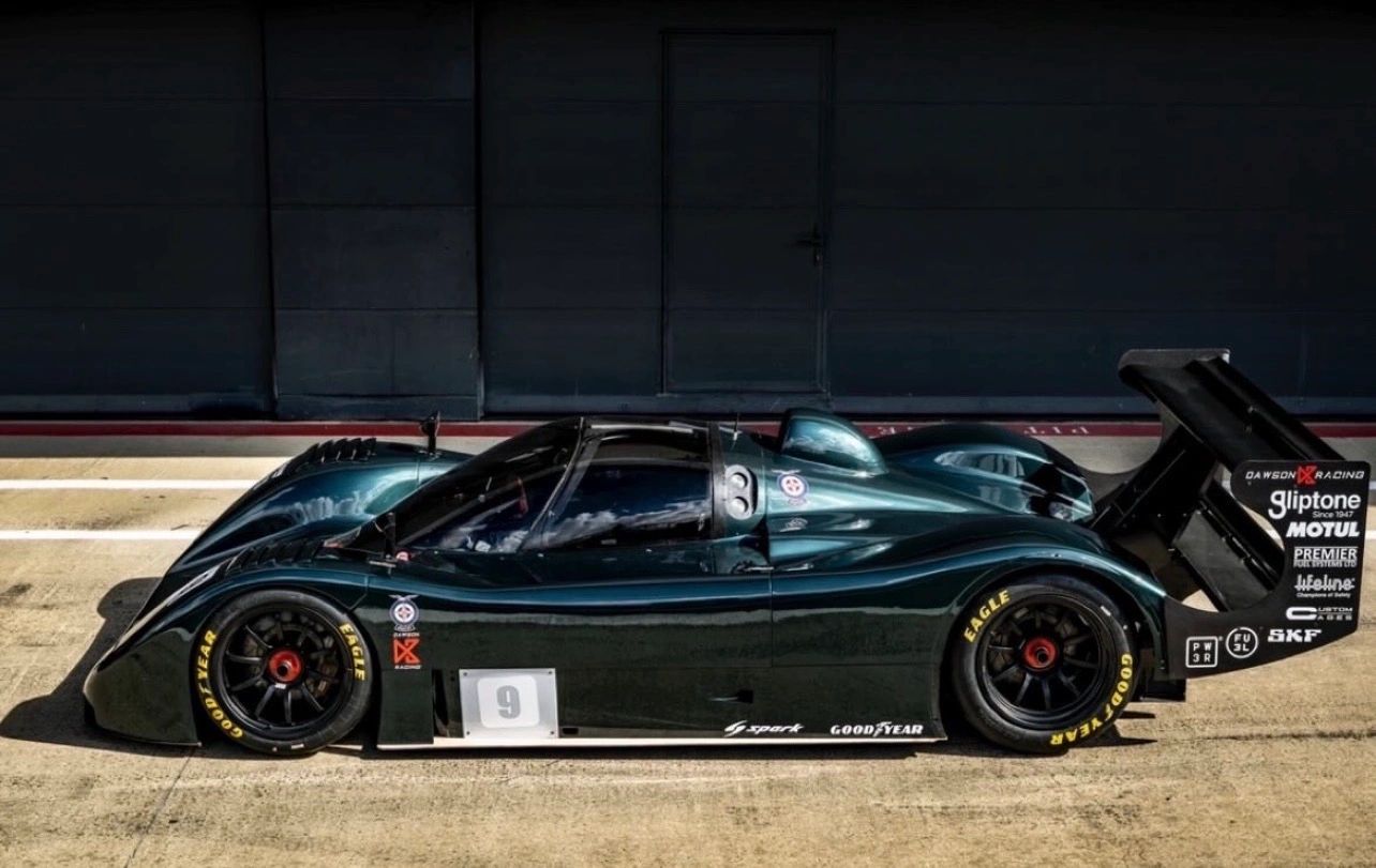 Sleek black race car with large rear wing and sponsor decals.