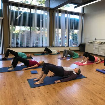 Pilates Group MAT class in Plymouth Canton does the MAT bridge exercise for gluts & hamstrings