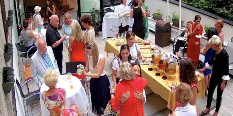 People socializing, table with drinks on it, yellow tablecloth